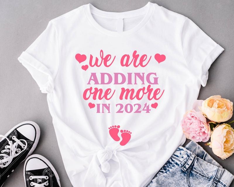 Valentine Pregnancy Announcement Shirt, We're adding one More in 2024 T-Shirt, Pregnancy Reveal Tee, New Mother Gift Shirt, Mommy To Be Short Sleeve, Expecting Mom Shirt.